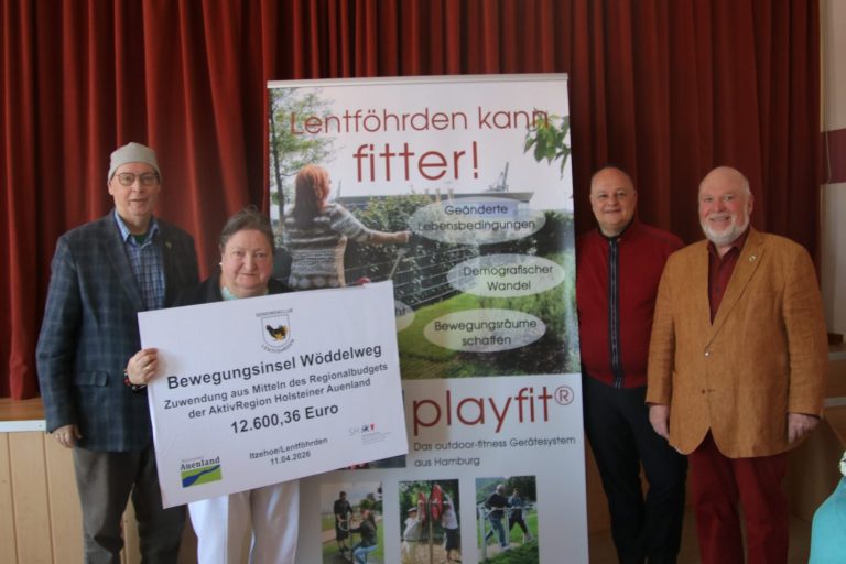 Vier Personen präsentieren einen Fördermittel-Scheck vor einem Banner 