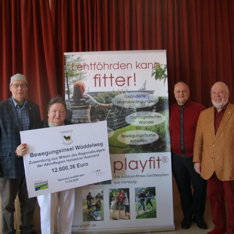 Vier Personen stehen vor einem Banner über Gesundheit und Fitness, halten einen Scheck.