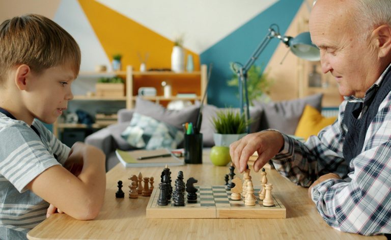 Kinder und alter Mann beim Schachspielen