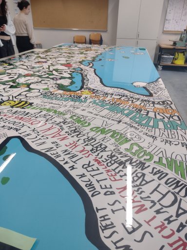 Bunte Tischoberfläche mit Textelementen und grafischen Darstellungen von Landkarten.