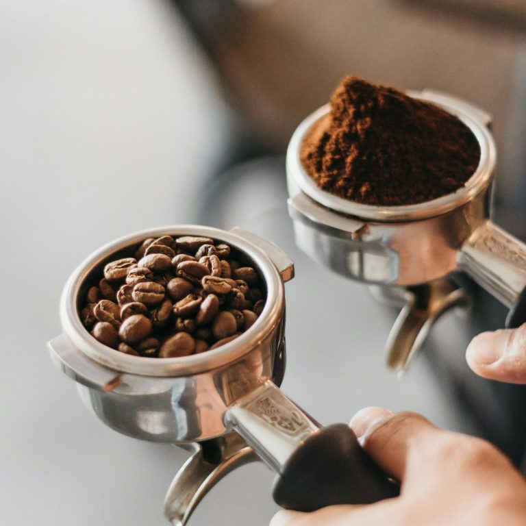 Zwei Siebträger mit jeweils Kaffeebohnen und Kaffeepulver