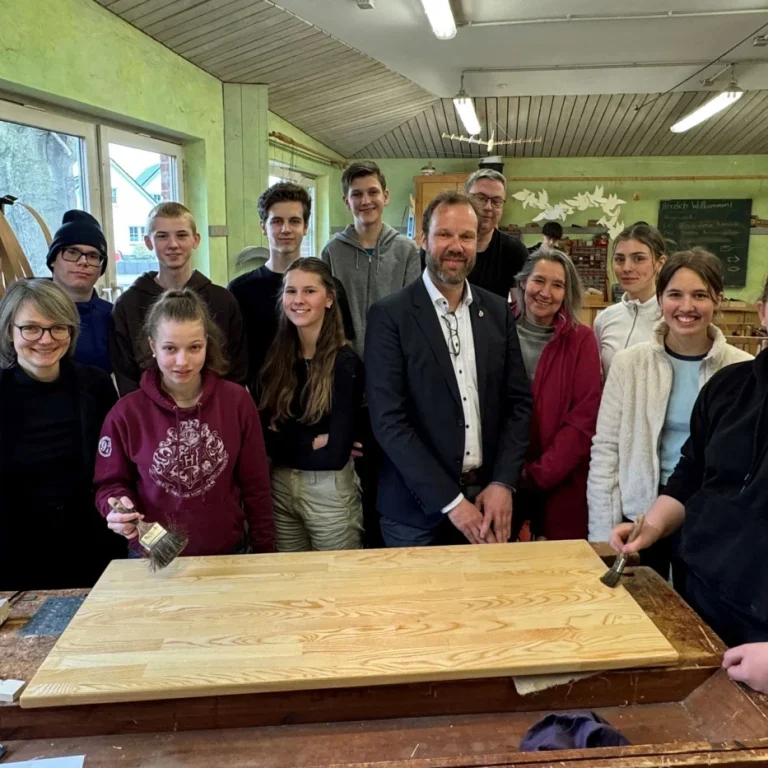 Gruppe von Menschen in einer Werkstatt, die zusammen an einem Holzprojekt arbeiten.