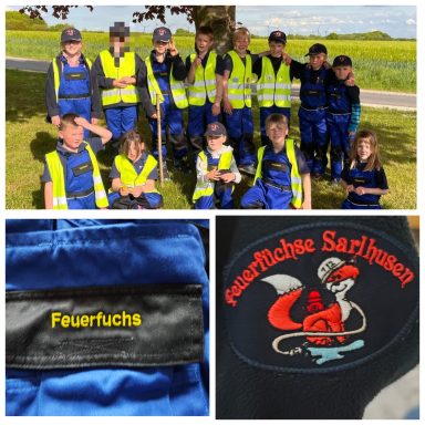 Gruppe von Kindern in Schutzkleidung mit Feuerwehrmotiven im Freien.