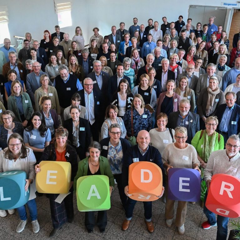 Gruppierung von Menschen, die "LEADER" in bunten Buchstaben halten.