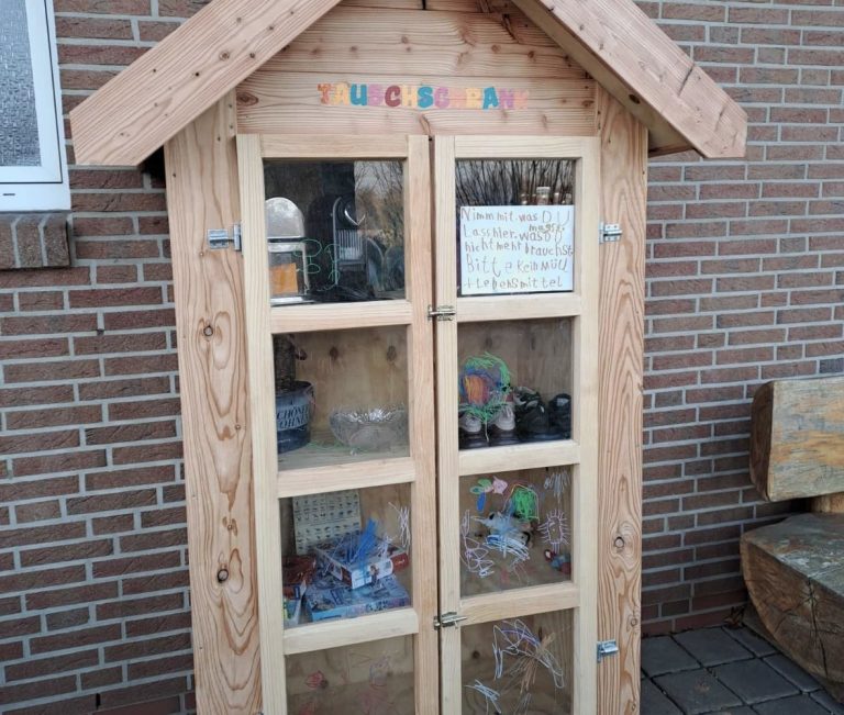 Holzschrank mit Glasfenstern, gefüllt mit verschiedenen Gegenständen und Notizen.