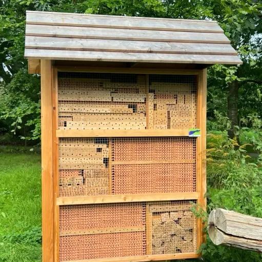 Insektenhotel aus Holz mit mehreren Fächern zur Förderung von Nützlingen in Gärten.
