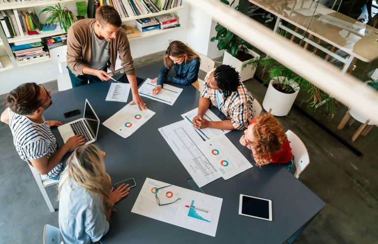 Planspiel Mitarbeiter arbeiten gemeinsam an Grafiken und Plänen am Tisch in einem modernen Büro.